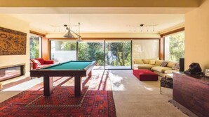 A spacious room with a pool table, a sofa, and a large window offering a view of the outdoors. - Farm Paradise in Douro 10 People (Baiao)