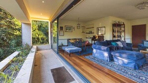 A living room with a sofa set, a dining area, and a view of greenery outside. - Farm Paradise in Douro 10 People (Baiao)