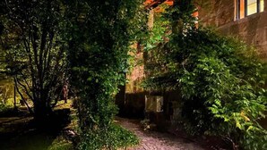 A stone building with a brick pathway leading to a wooden door, surrounded by lush greenery. - Farm Paradise in Douro 10 People (Baiao)