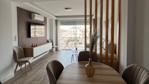 Un comedor moderno con una mesa redonda de madera, sillas acolchadas y un jarrón decorativo.