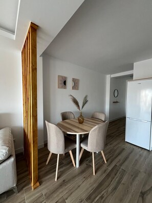 Cocina moderna con refrigerador blanco, una mesa de comedor con sillas y dos adornos colgantes.