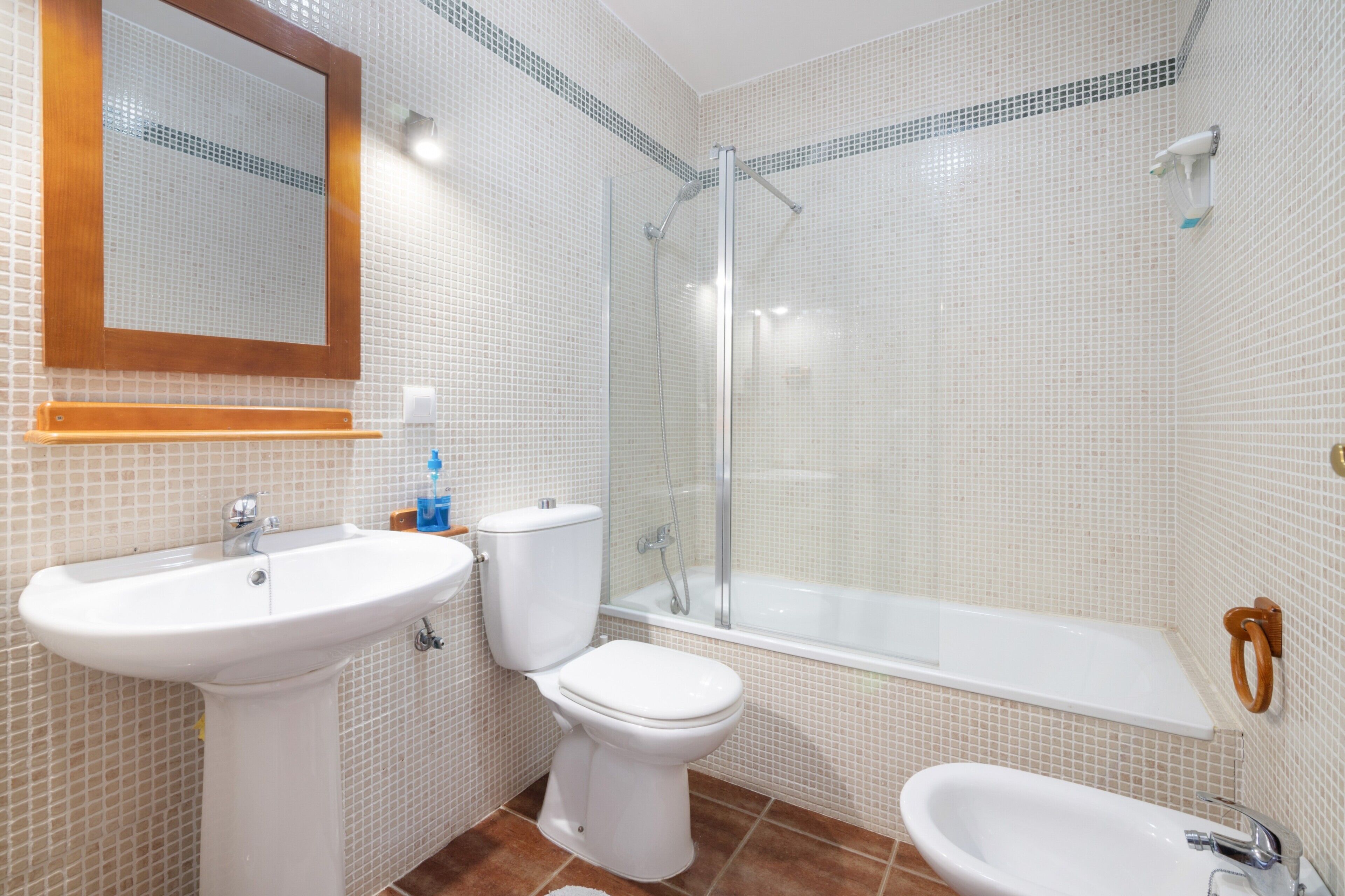 Een badkamer met een wastafel, toilet, douche en bad.