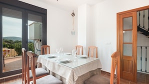 Un espace repas avec une table en verre, des chaises et une vue sur l’extérieur.