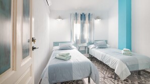 Une chambre d’hôtel avec deux lits, une porte, un appareil de climatisation, une petite table et un tapis à motifs.