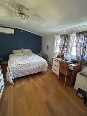 A bedroom with a bed, a desk, a chair, a ceiling fan, and a window with curtains. - Fabulous 4-bedroom house in East Meadow perfect for your getaway (East Meadow)