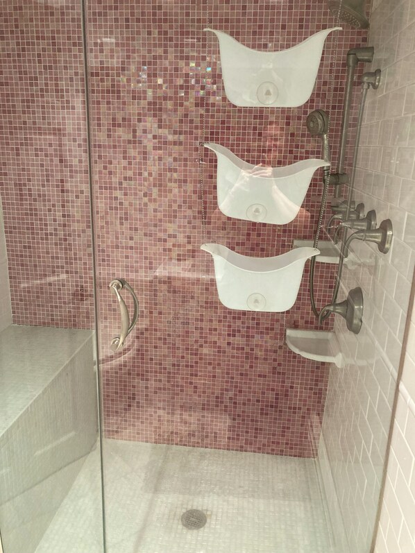 Un espace douche doté d’une paroi en verre, d’une barre d’appui et d’un mur carrelé.