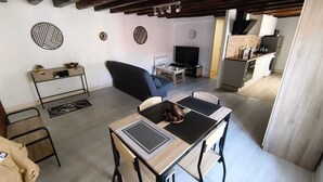 Een moderne woonkamer met een eethoek, een televisie en een keuken op de achtergrond.