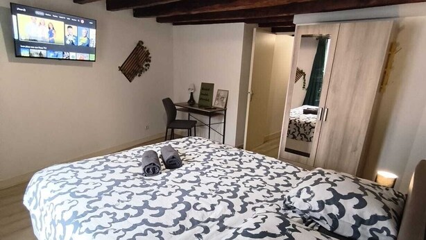 Een slaapkamer met een bed, een bureau, een stoel en een televisie aan de muur.