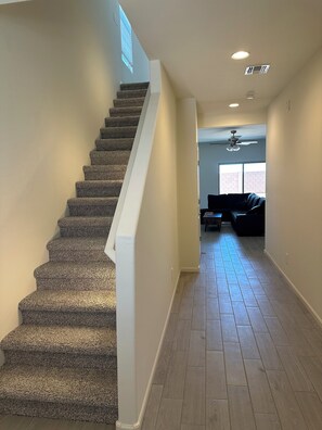 A staircase leading to a living area with a ceiling fan and a window. -  4-bedroom in superb Tucson, Fully Furnished Escape Near Scenic Desert Trails (Tucson)