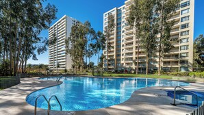 A swimming pool with a 1.25m depth marker, surrounded by a concrete deck and metal railings, with tall residential buildings in the background. - Relaxing Family Condo with Ocean View & Pools in Costa Algarrobo (El Yeco)