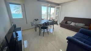 Una stanza con un tavolo da pranzo, sedie, un divano, una TV e una finestra con vista.