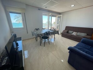 Ein Zimmer mit Esstisch, Stühlen, einer Couch, einem Fernseher und einem Fenster mit Blick.
