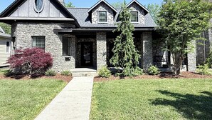 Une maison en pierre avec un porche à l’avant, une allée et une pelouse bien entretenue.