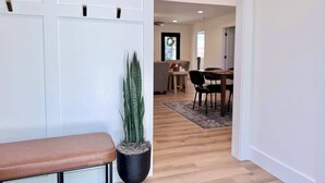 Un couloir avec un banc, une plante en pot et, au fond, un coin repas.