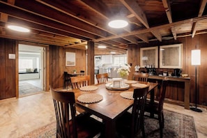 A wooden dining area with a large table, chairs, and a kitchen in the background. - Private Lakefront Peninsula Retreat with Hot Tub (Kingsport)