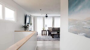 Un pasillo que conduce a una sala de estar con un sofá, una mesa de centro y un cuadro en la pared.