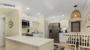Une cuisine moderne avec des meubles blancs, un réfrigérateur en acier inoxydable et un îlot central.