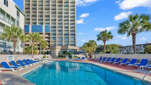A swimming pool with lounge chairs, a high-rise building, and palm trees. - Ocean Forest Plaza 912 (Myrtle Beach)