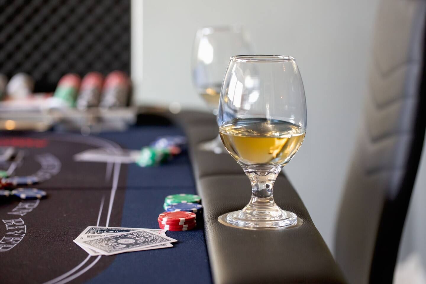 A poker table with chips, a glass of white wine, and playing cards.