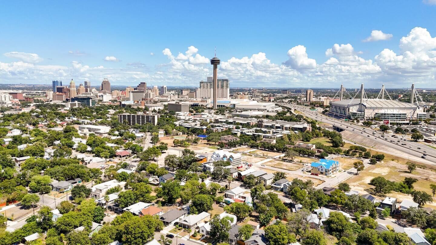 An aerial view of a cityscape with a prominent tower, a bridge, and a mix of residential and commercial buildings.