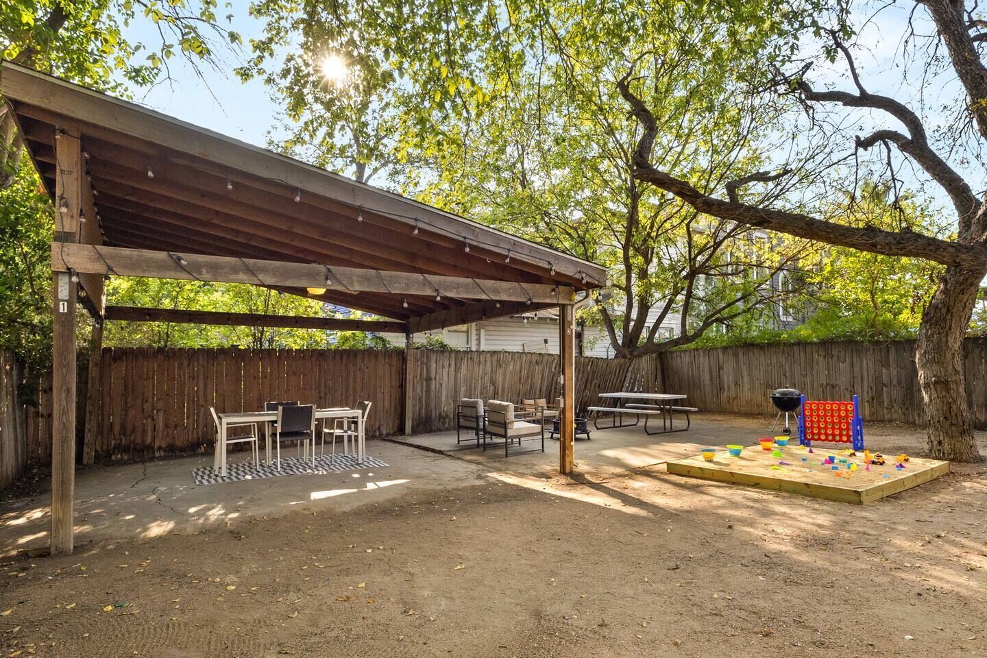 A covered patio area with tables and chairs, a barbecue grill, and a children's play area.