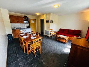 A compact living space with a dining area, kitchen, and a red sofa. - 1st floor, swimming pool, sauna, balcony, parking, tv, ski locker, 49m², Saint Gervais (Saint-Gervais-les-Bains)