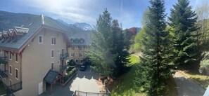 A residential area with multi-story buildings, a parking area, and a pathway surrounded by trees. - 1st floor, swimming pool, sauna, balcony, parking, tv, ski locker, 49m², Saint Gervais (Saint-Gervais-les-Bains)