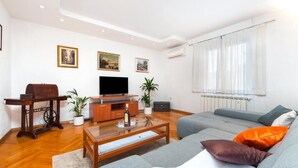 Ein Wohnzimmer mit einer Couch, einem Couchtisch, einem Fernseher und einer Vintage-Nähmaschine.