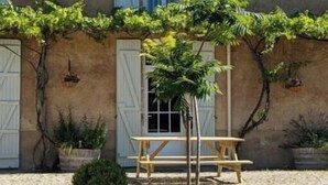 A building with a tiled roof, a wooden bench, and potted plants. - Gîte Bambou - Country charm and heated swimming pool in the heart of Charente (Chadurie)