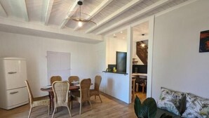 A dining area with a table and chairs, a kitchenette, a sofa, and a plant. - Gîte Bambou - Country charm and heated swimming pool in the heart of Charente (Chadurie)