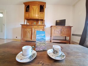 Ein Zimmer mit einem Holzkasten, einem Fernseher und zwei Tassen auf einem Tisch.