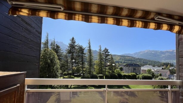 Un balcone con vista su un paesaggio montuoso, un pontile in legno e una ringhiera in metallo.