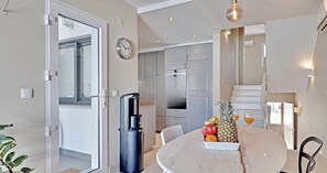 Eine moderne Küche mit Edelstahlgeräten, ein Essbereich mit einem Marmortisch und eine Treppe, die zu einer oberen Ebene führt.