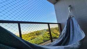 Eine Hängematte auf einem Balkon mit Blick auf grüne Hügel.