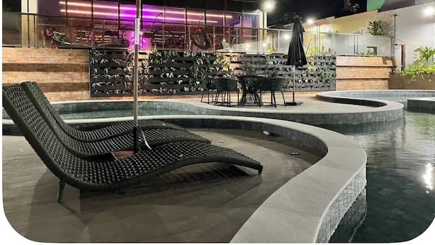 Ein Poolbereich mit Liegestühlen, einem Tisch und einer Bar mit Neonbeleuchtung.