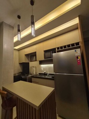 A modern kitchen with a central island, stainless steel appliances, and pendant lighting. - Cabo Branco Altiplano João Pessoa - Modern, cozy, family-friendly apartment (João Pessoa)