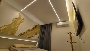 Ein modernes Schlafzimmer mit Bett, Wand-Fernseher und Klimaanlage.
