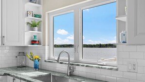 Eine Küche mit Spüle, Fenster und Blick auf ein Gewässer.