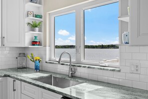 Eine Küche mit Spüle, Fenster und Blick auf ein Gewässer.
