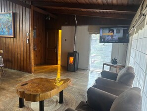 A living room with a wooden table, a sofa, a television, and a fireplace.