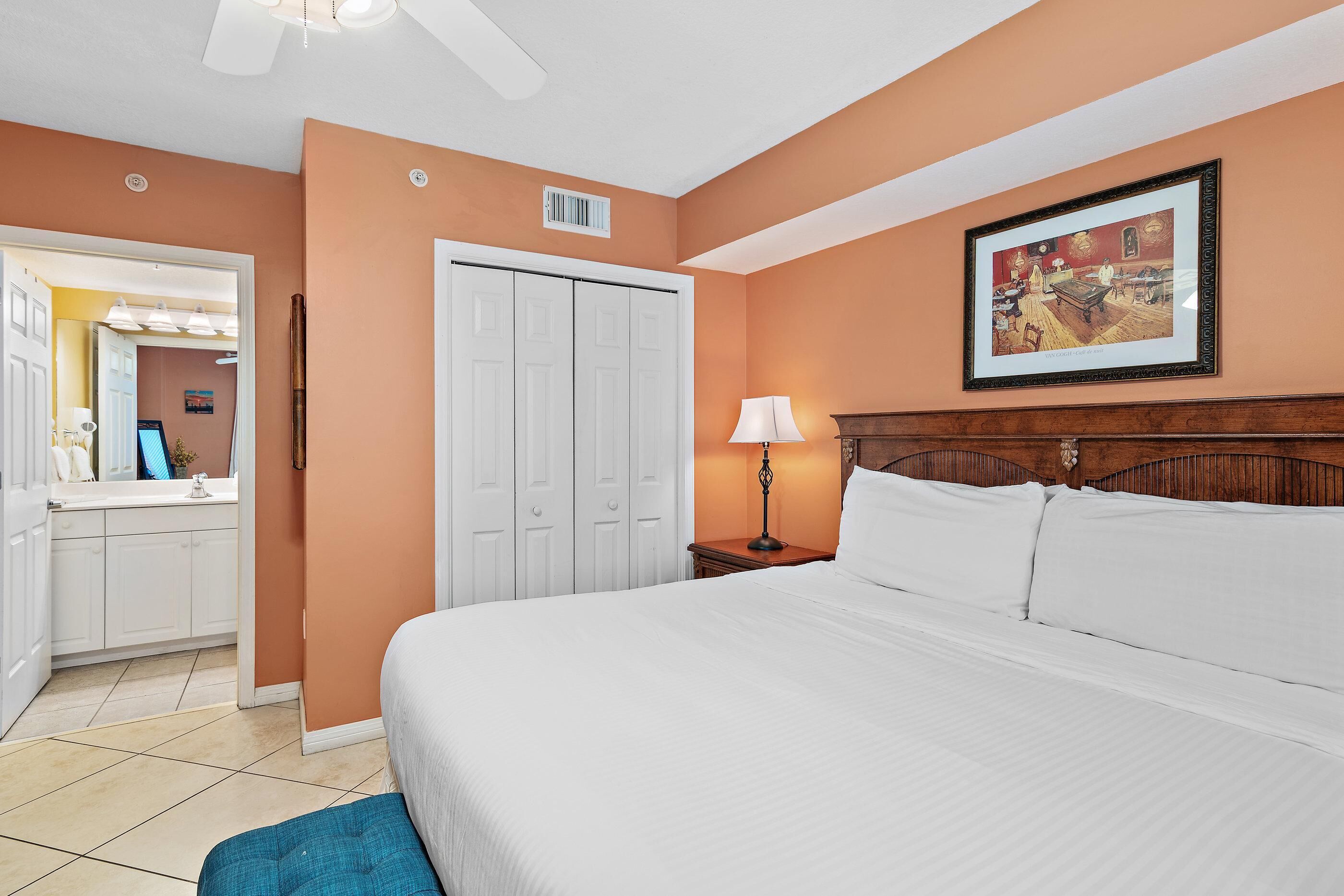 A bedroom with a bed, a nightstand, a lamp, a wardrobe, and a framed picture on the wall.