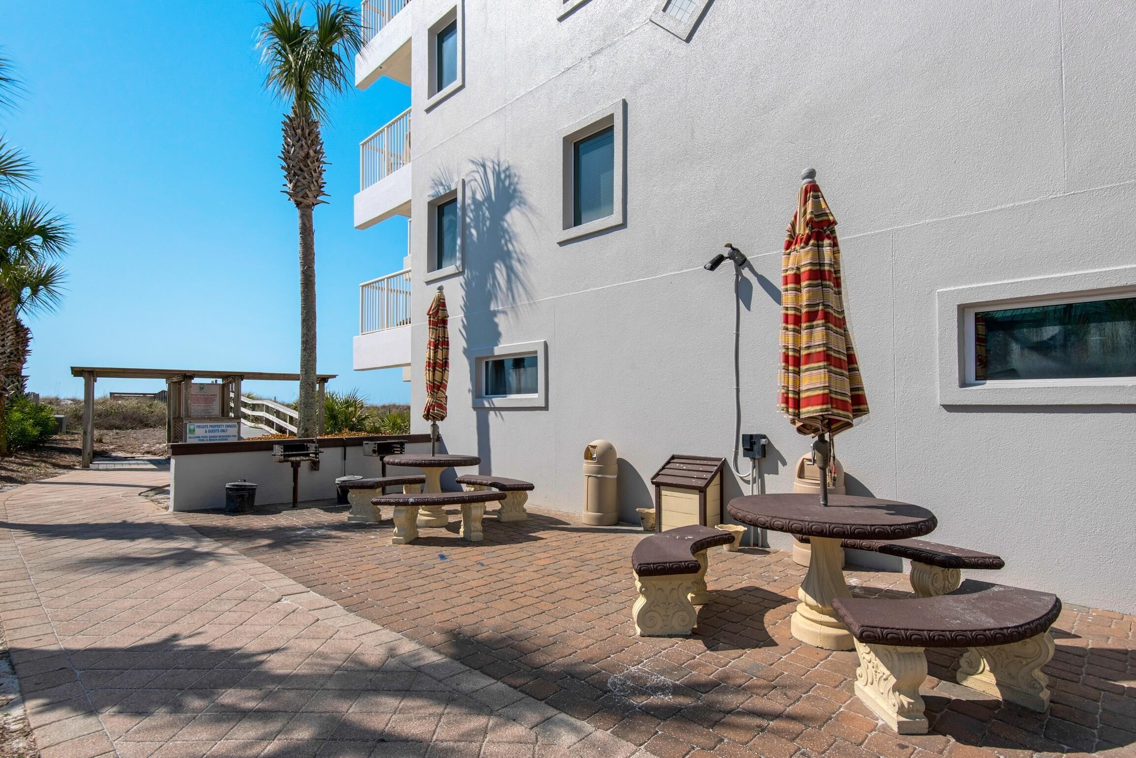 Un patio con mobiliario exterior, incluyendo mesas y bancos, y sombrillas.