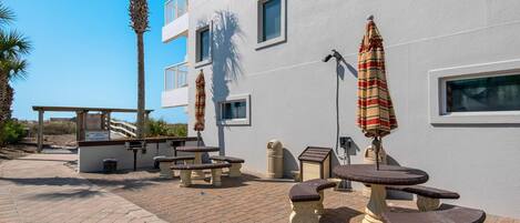 Un patio con mobiliario exterior, incluyendo mesas y bancos, y sombrillas.