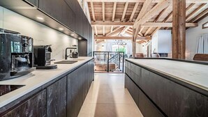 Una cucina moderna con mobili scuri, una macchina da caffè espresso integrata e un soffitto in legno.