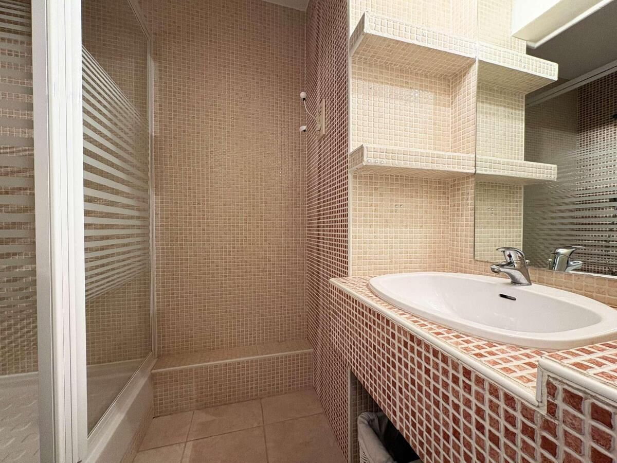 A bathroom with a shower, a sink, and a mirror.