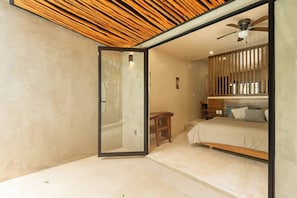 A bedroom with a wooden ceiling, a bed, a desk, and a shower area. - NEW Apartment AREIA Tulum 1BR Style/Comfort (Tulum)