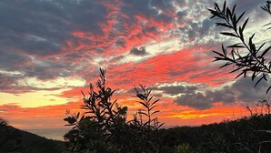 Un atardecer con nubes, vegetación y una vista distante.