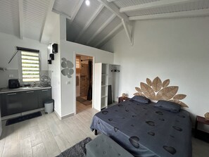 A bedroom with a bed, a bathroom, and a kitchenette. - Bungalow in the heart of nature  (Deshaies)