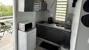 Cocina pequeña con microondas, cafetera y lavabo.