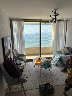 A living room with a large window, a sofa, a coffee table, and a child playing. - Disegni 15 - First line apartment Sea view and relaxation (Coquimbo)
